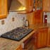 red-oak-cabinetry-juparana-gold-granite-and-travertine-backsplash